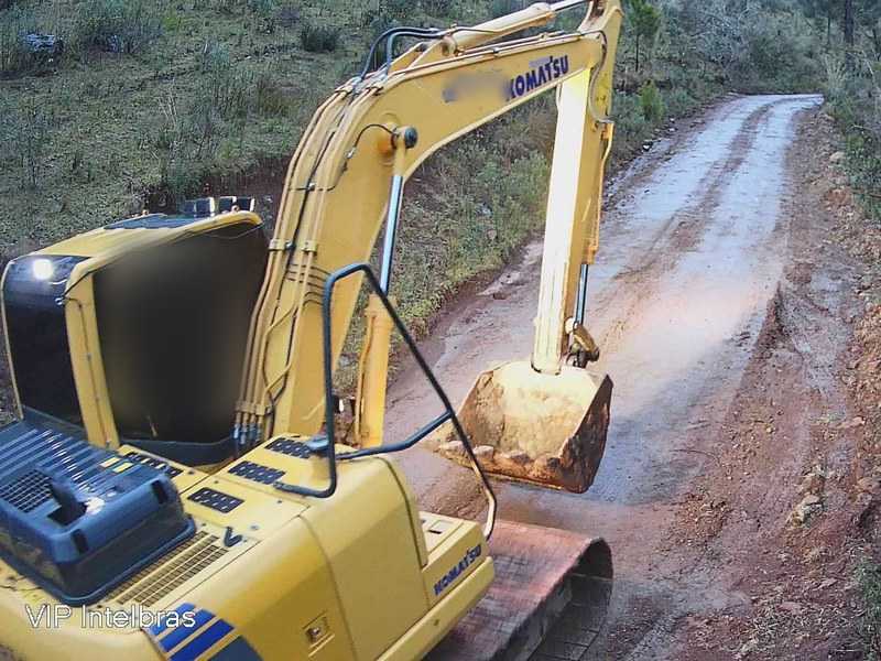 Escavadeira trabalhando em estrada de terra no meio da mata